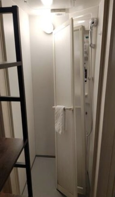 外れて斜めに立てかけられたシャワー室の折れ戸